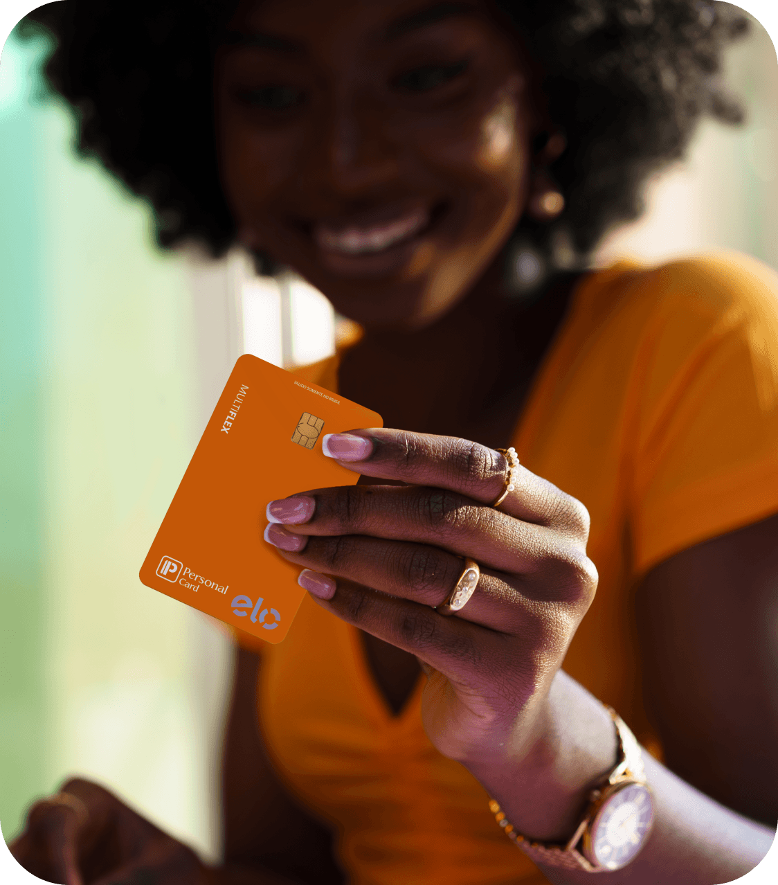 Mulher sorrindo segurando cartão Personal Card laranja com chip dourado